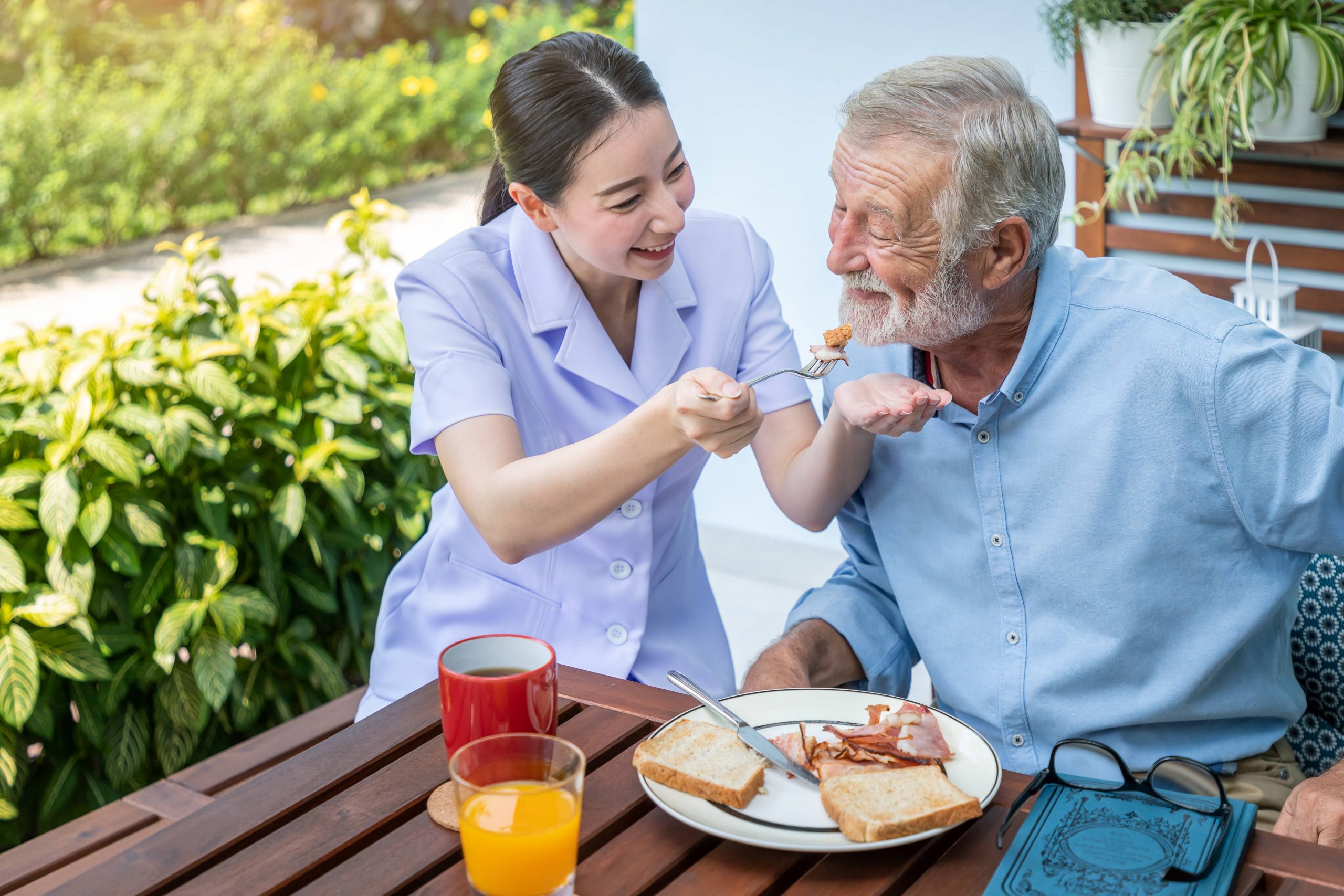 Caregiver feeding elderly senior man