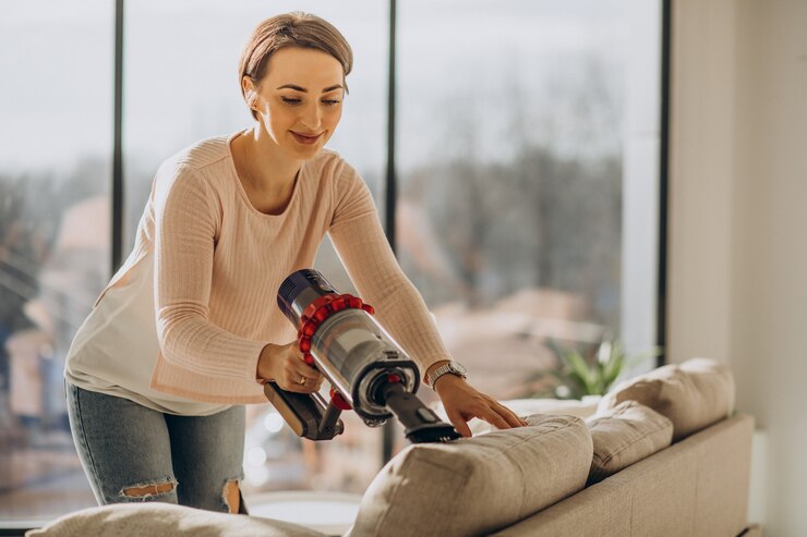young woman with rechargeable vacuum cleaner cleaning at home